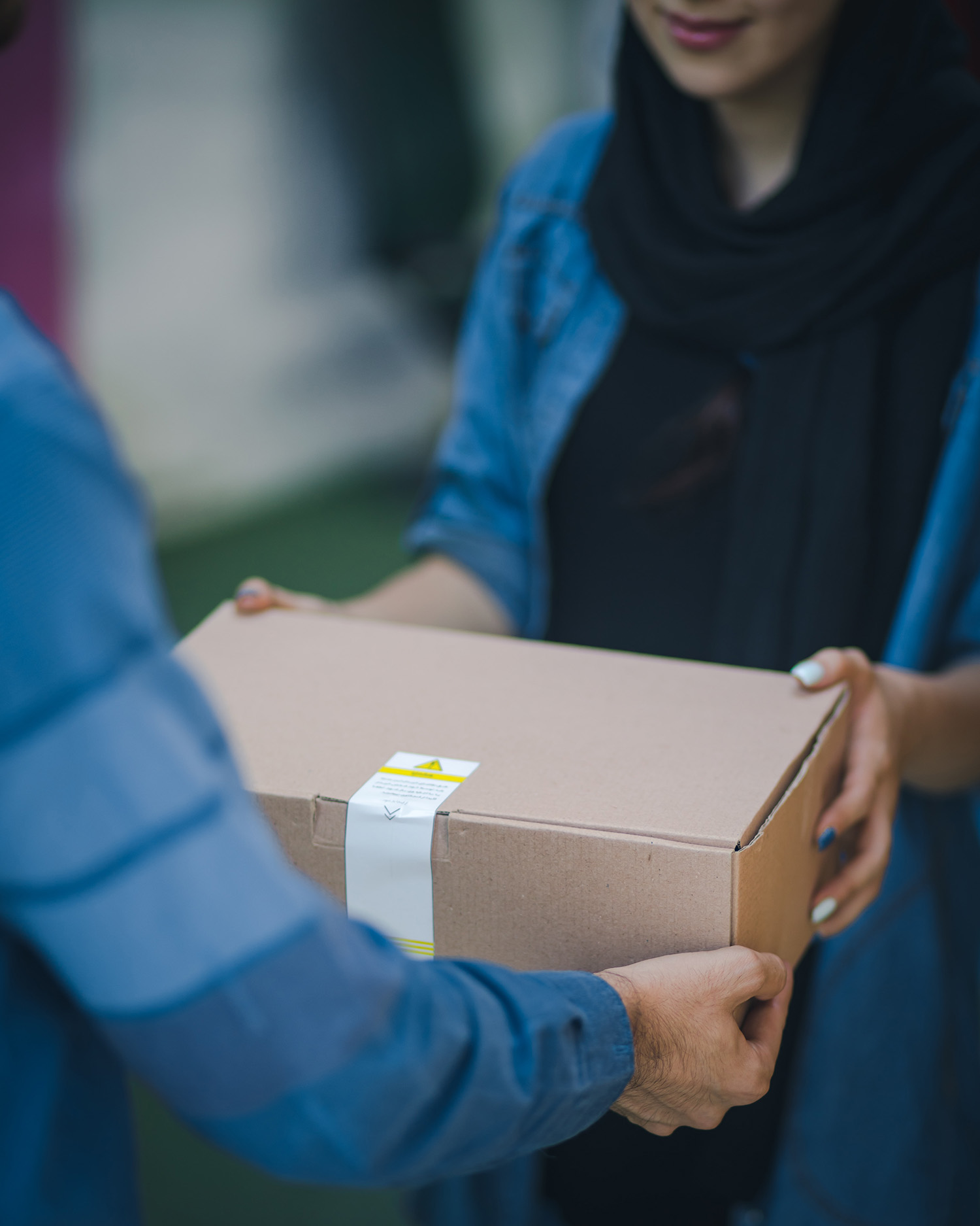 Woman wearing hijab handing off a cardboard box